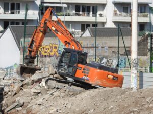 an orange excavator digging through a pile of rubble