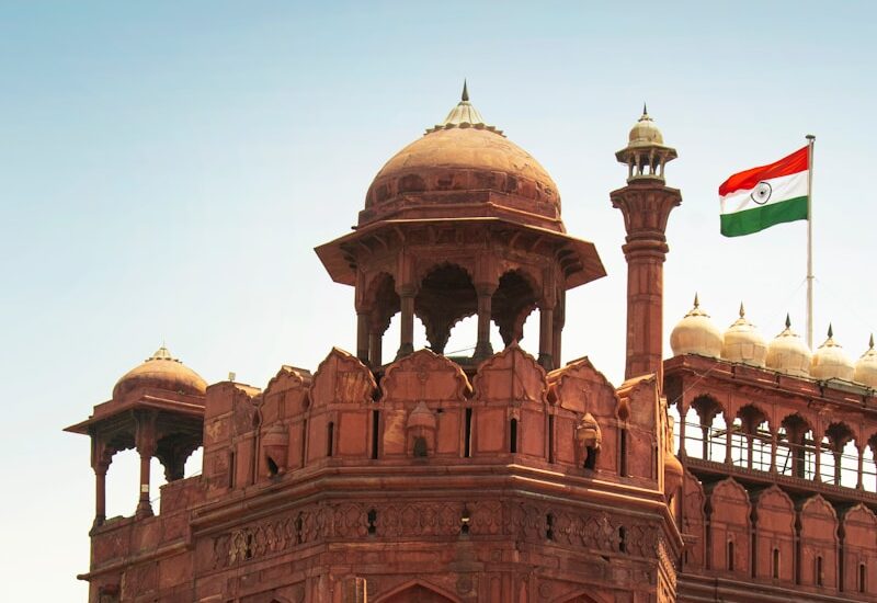a large building with a flag on top with Red Fort in the background