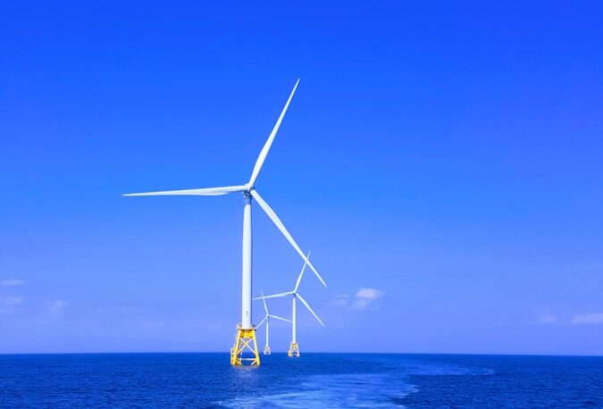 three white wind turbine on sea