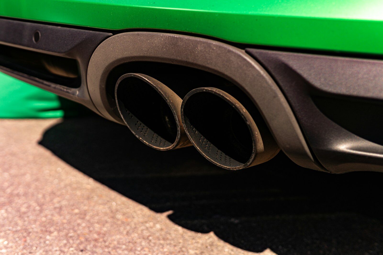 Dark dual exhaust pipes on a vibrant green car